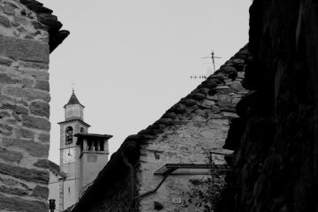 Foto in bianco e nero del campanile di Oira e delle case antiche