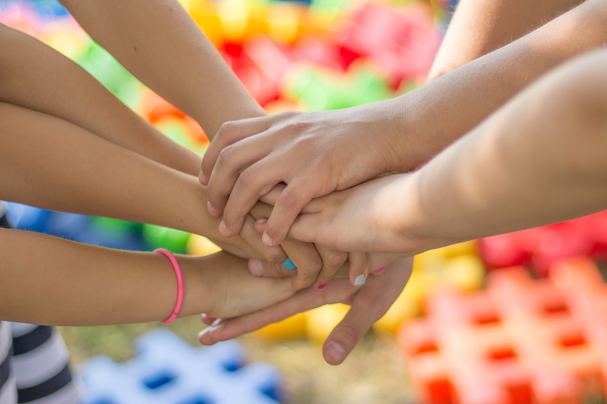mani che si intrecciano in segno di amicizia su sfondo colorato