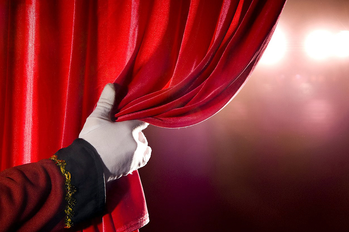 mano che tira una tenda rossa a teatro