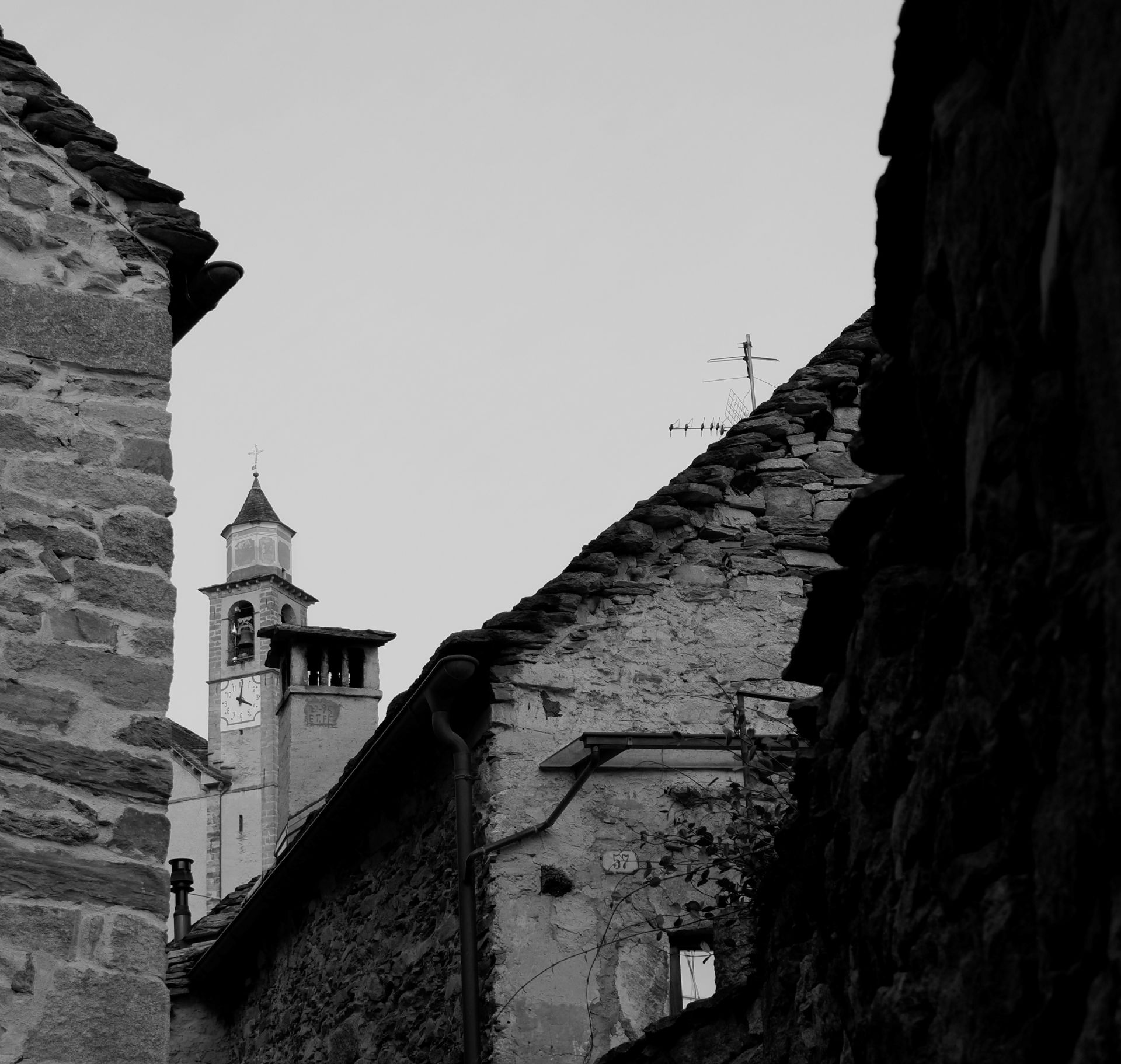 Foto in bianco e nero del campanile di Oira e delle case antiche